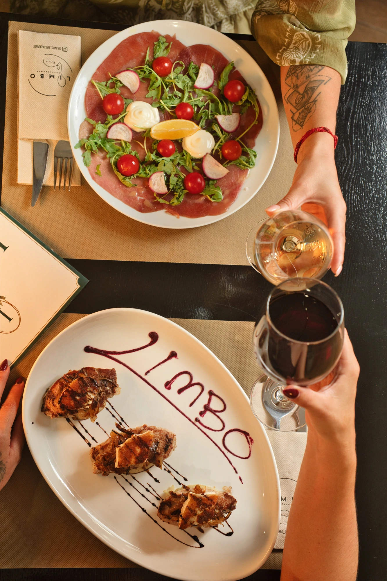 Mesa vista desde arriba con dos platos, copas de vino y el plato con la palabra Limbo